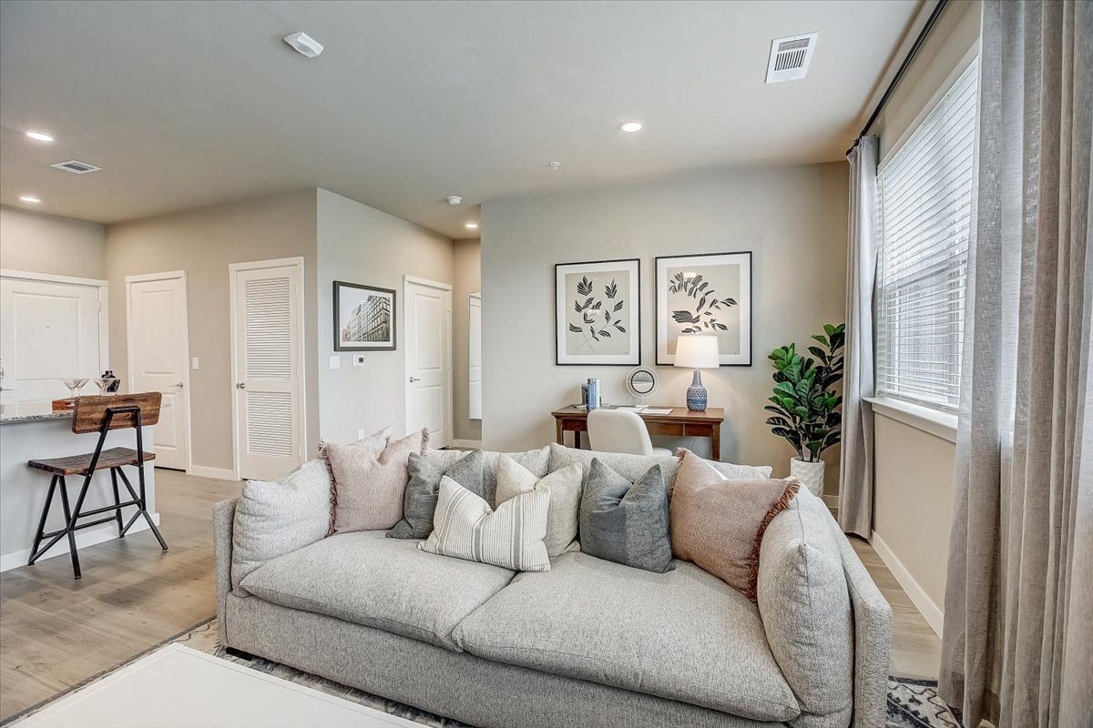 Living room with plush sofa, work desk, and natural light from a large window.